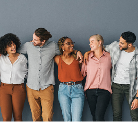 A diverse group of people linking arms and looking at each other in front of a slate-gray background.