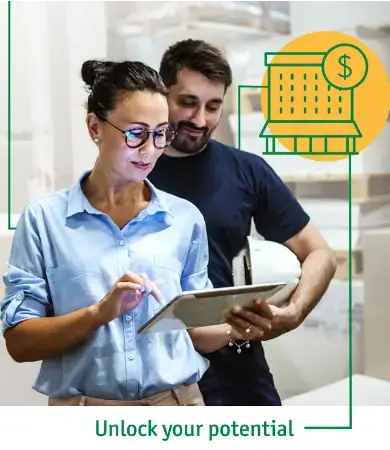 Cropped Photo of Construction plans being reviewed by man holding a construction hat and woman holding an iPad while in a warehouse.