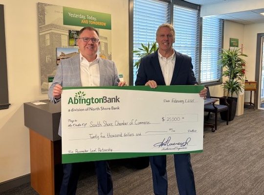 Two people holding a large check with a donation for South Shore Chamber of Commerce. 