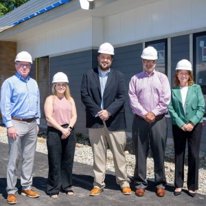 Four people with hard hats posed outside of a building project.