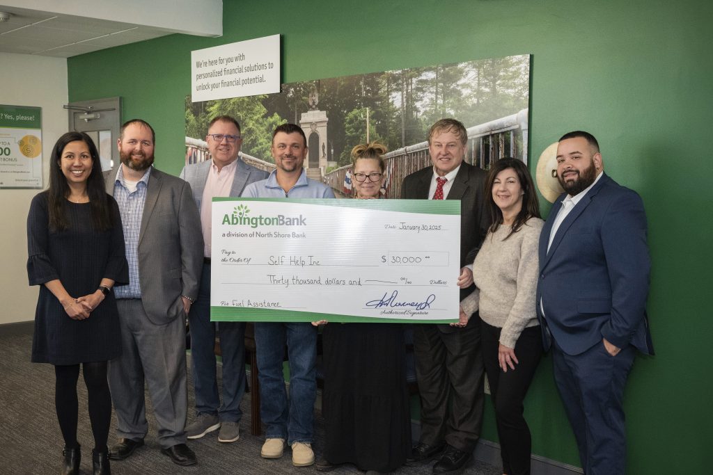 A group of people holding a large check donation for Self Help Inc. 