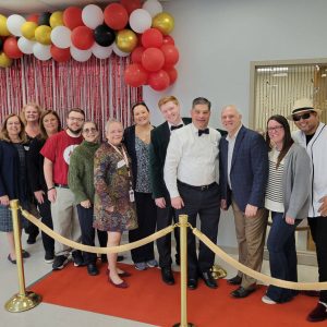 A group of people in formal clothing surrounded by colorful balloons and streamers.