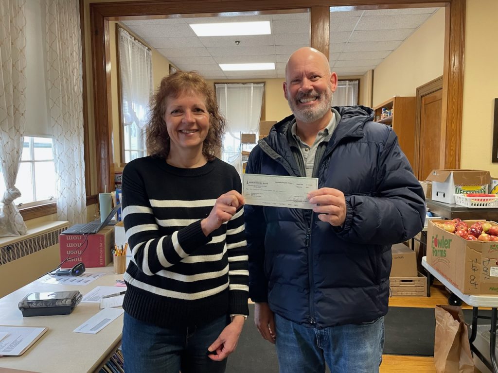 Two people holding a check donation to Reading Food Pantry. 