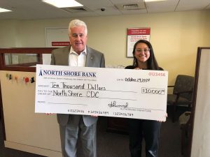 Two people holding a giant check for a donation.